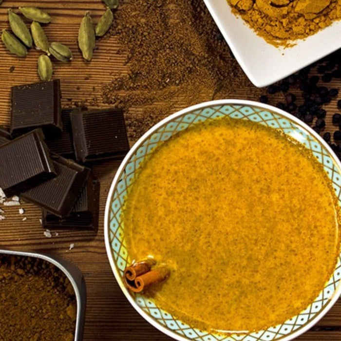 cup of hot goldenmilk with cacao and fresh spices on cutting board