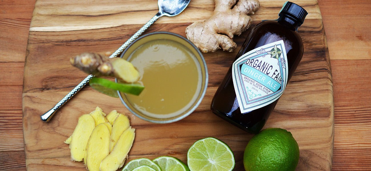 ginger ale drink and syrup on cutting board with fresh ginger and lime - organicfair.com