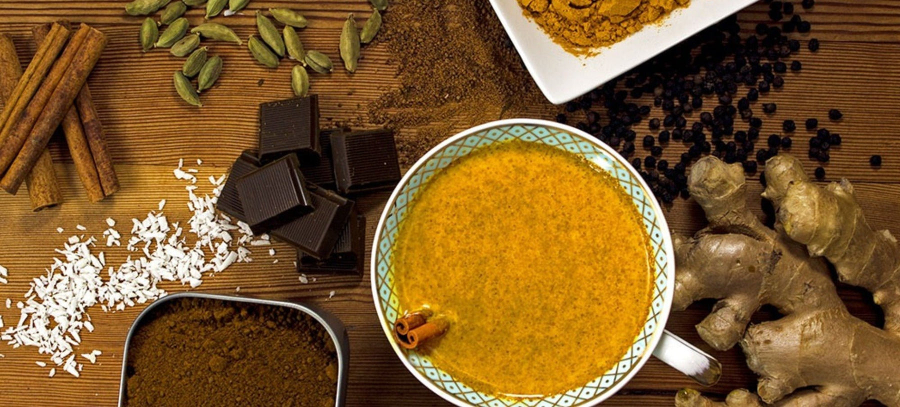 cup of hot goldenmilk with cacao and fresh spices on cutting board 